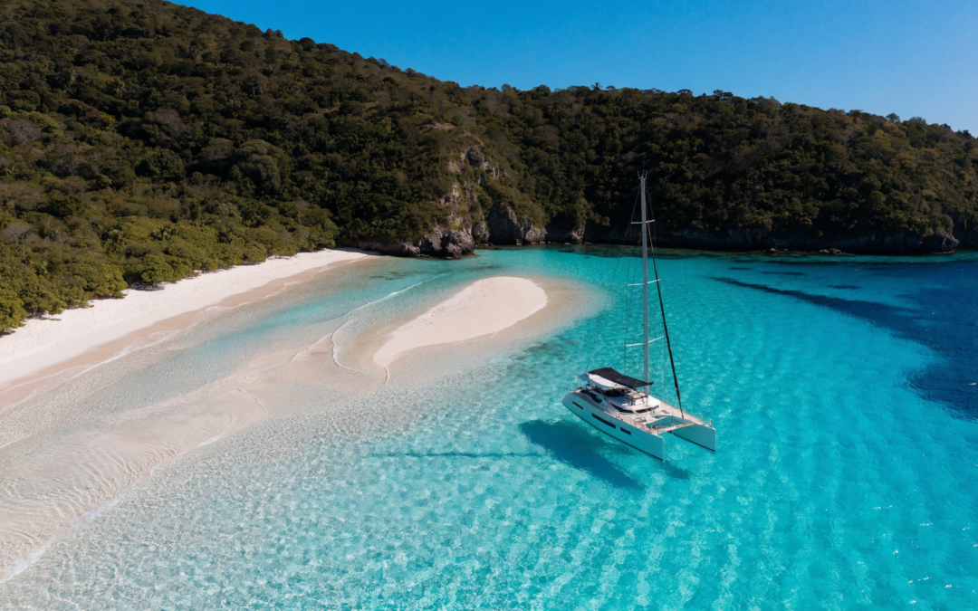 A luxury crewed catamaran anchored alone in a turquoise Caribbean cove